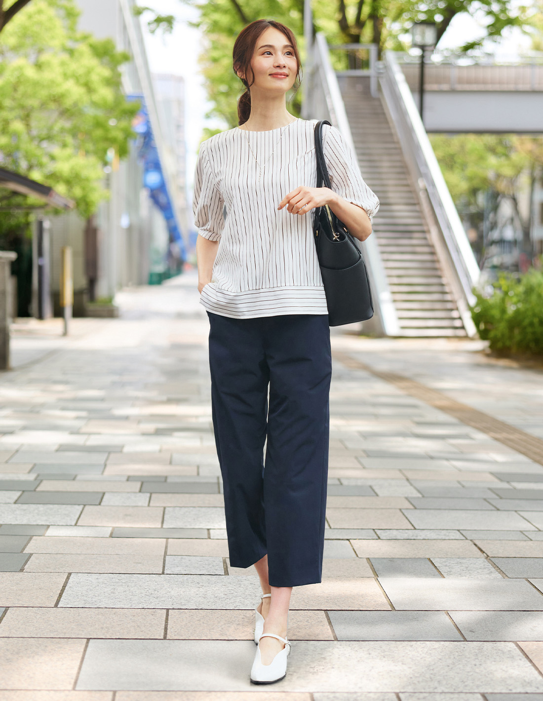 ネイビーのストレッチワイドパンツ・ホワイトのストライプタックプルオーバー・ビジューネックレスを着用した女性