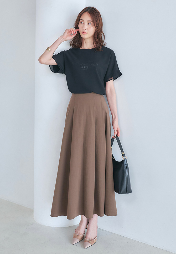 シアーレイヤードロゴ Tシャツ、ラッシュフレアスカートを着用した女性のアップの画像