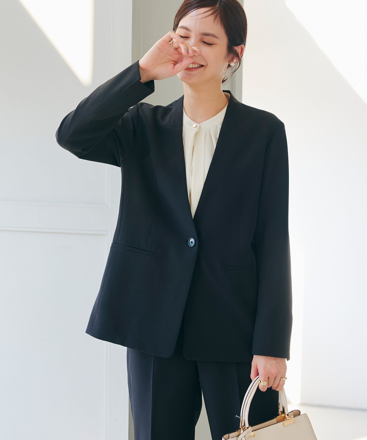 ブラックの《洗える・シワになりにくい》正解ノーカラージャケット・ブラックの《洗える・シワになりにくい》正解ワイドパンツ・オフホワイトの《シワになりにくい》シルキーサテン2WAYタックブラウスを着用した女性の画像（スライド）