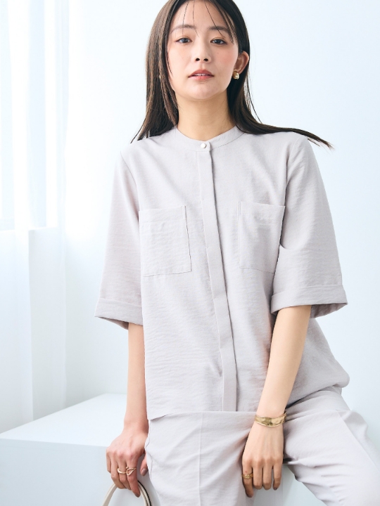 イエローのリネンライクバンドカラーハーフスリーブブラウス・ブルーのデニムを着用した女性