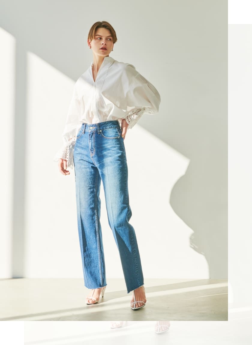 カットワークスリーブブラウス、デニムストレートワイドパンツを着用している女性の写真