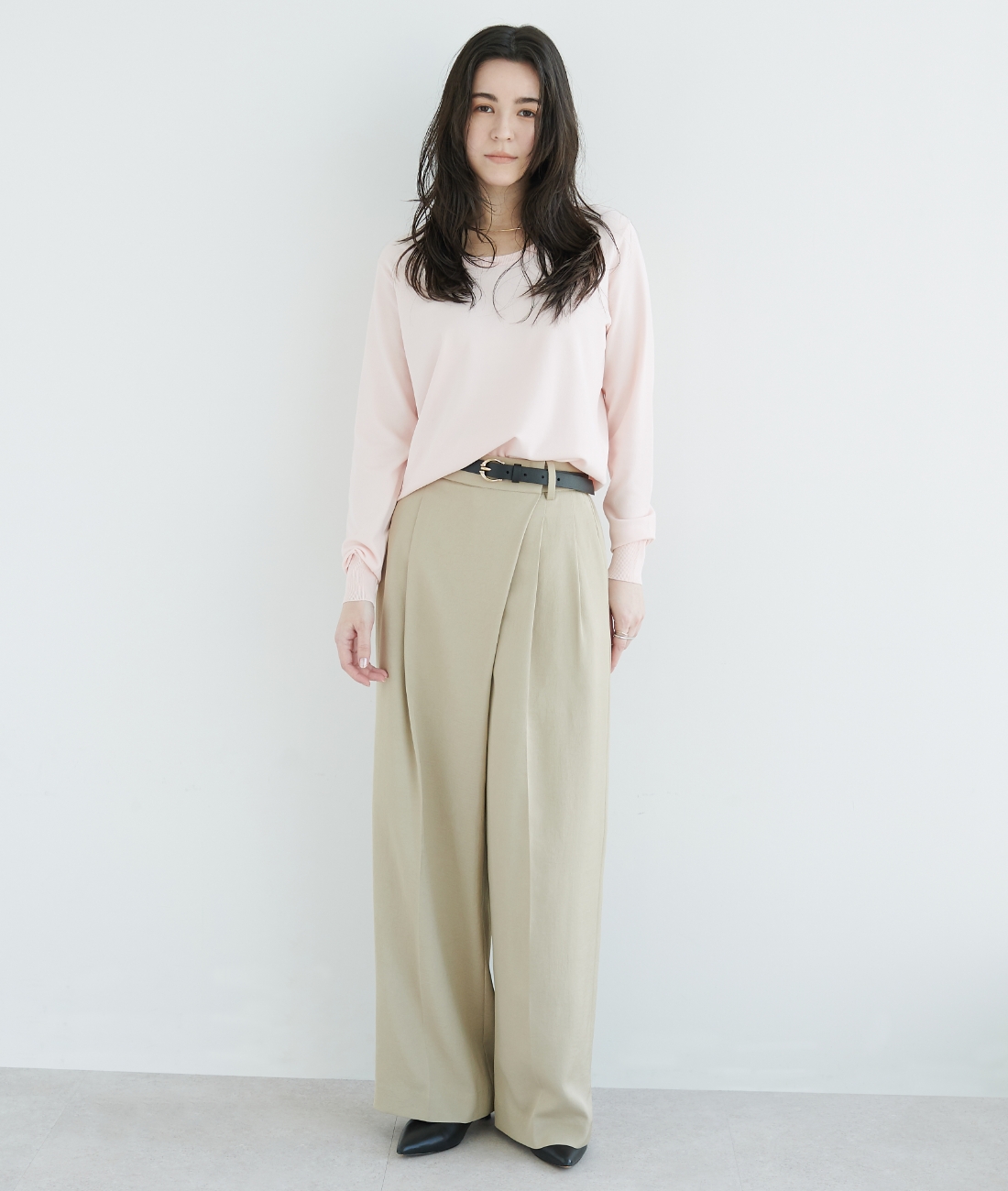 パステルピンクのニット・ベージュの【トリアセリネン】ラップトラウザーパンツを着用している女性の画像