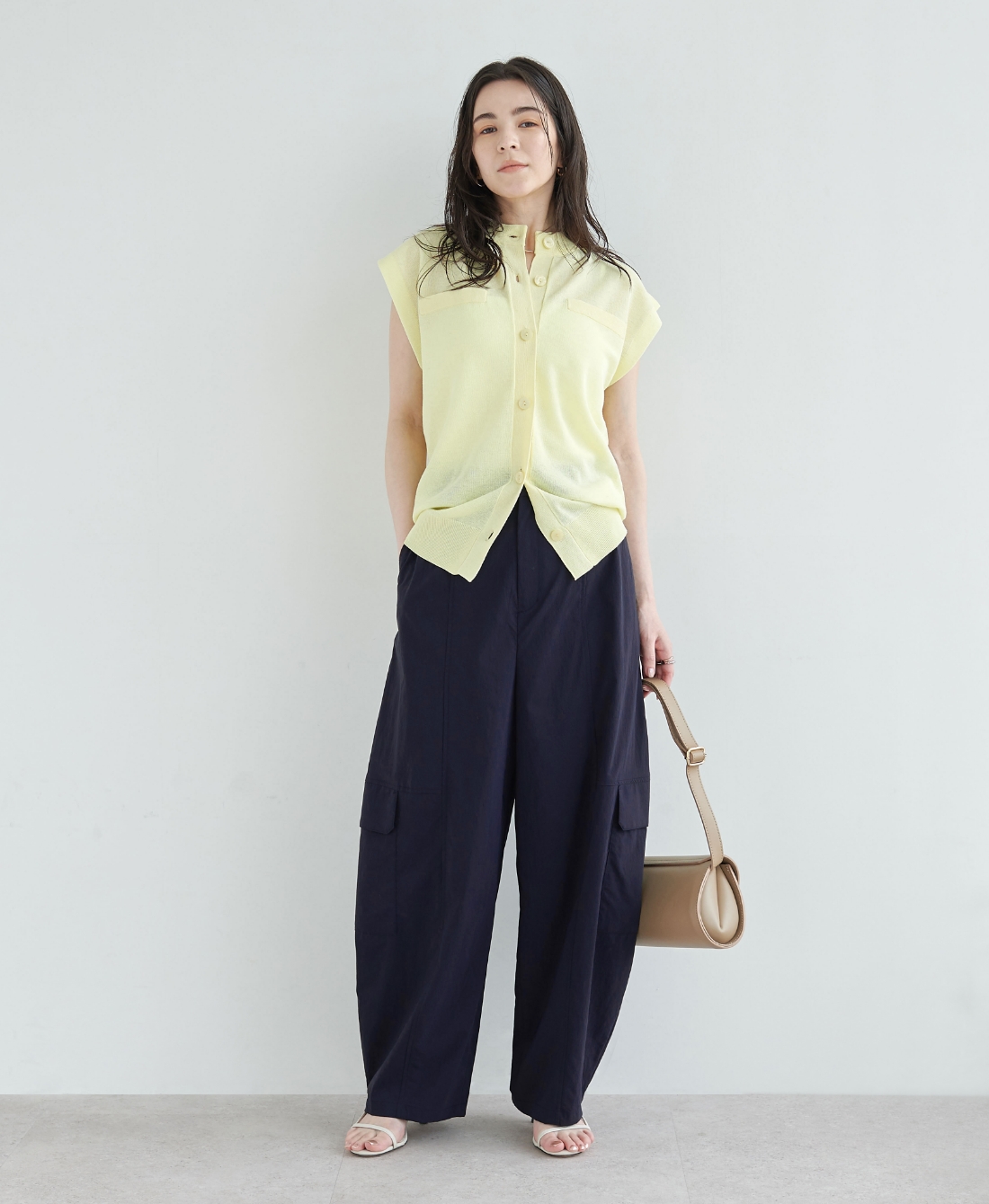 イエロー色のニットとネイビー色のナイロンタスランボリュームカーゴパンツ【AIRY MOTION】を着用した女性１