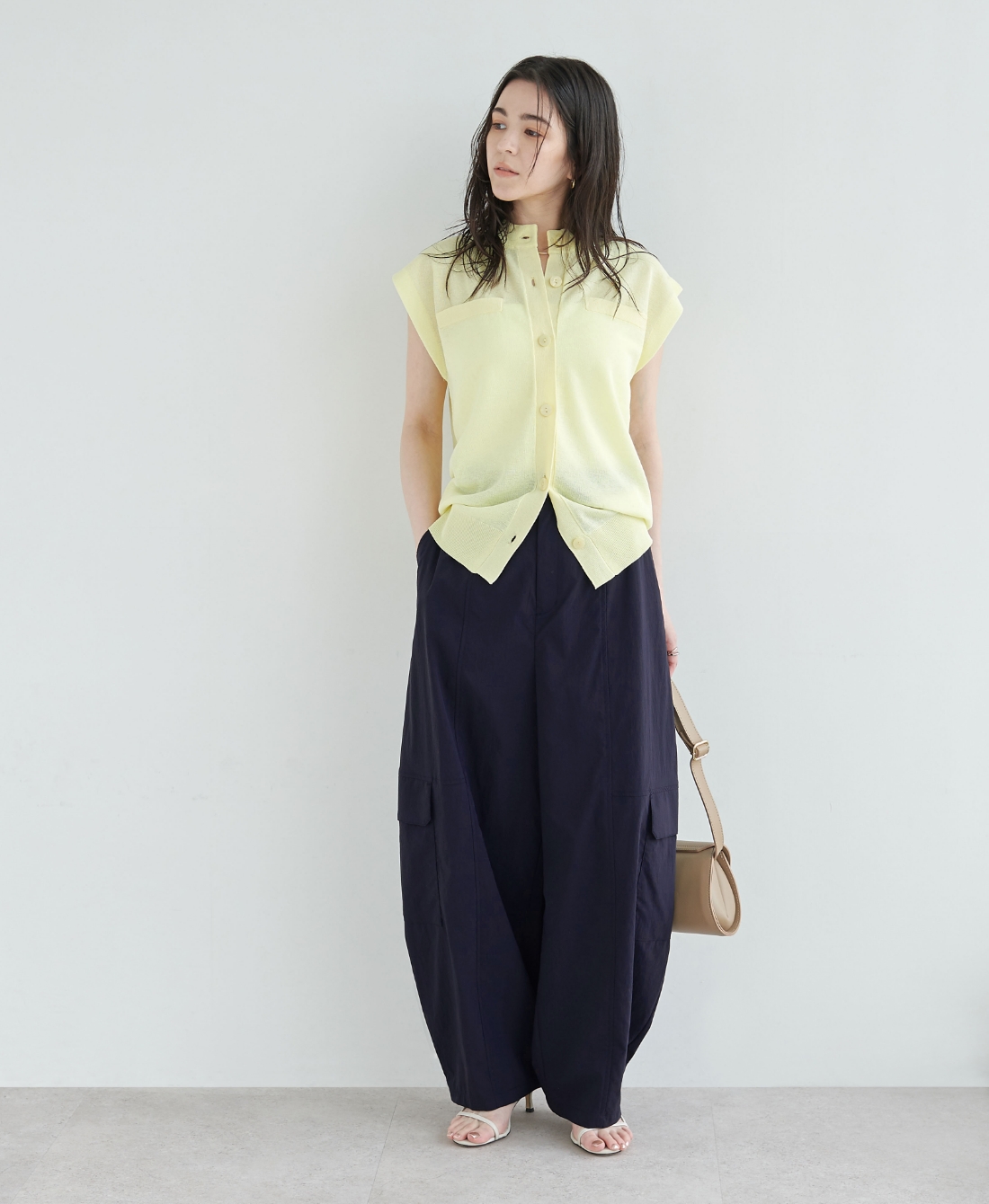 イエロー色のニットとネイビー色のナイロンタスランボリュームカーゴパンツ【AIRY MOTION】を着用した女性２