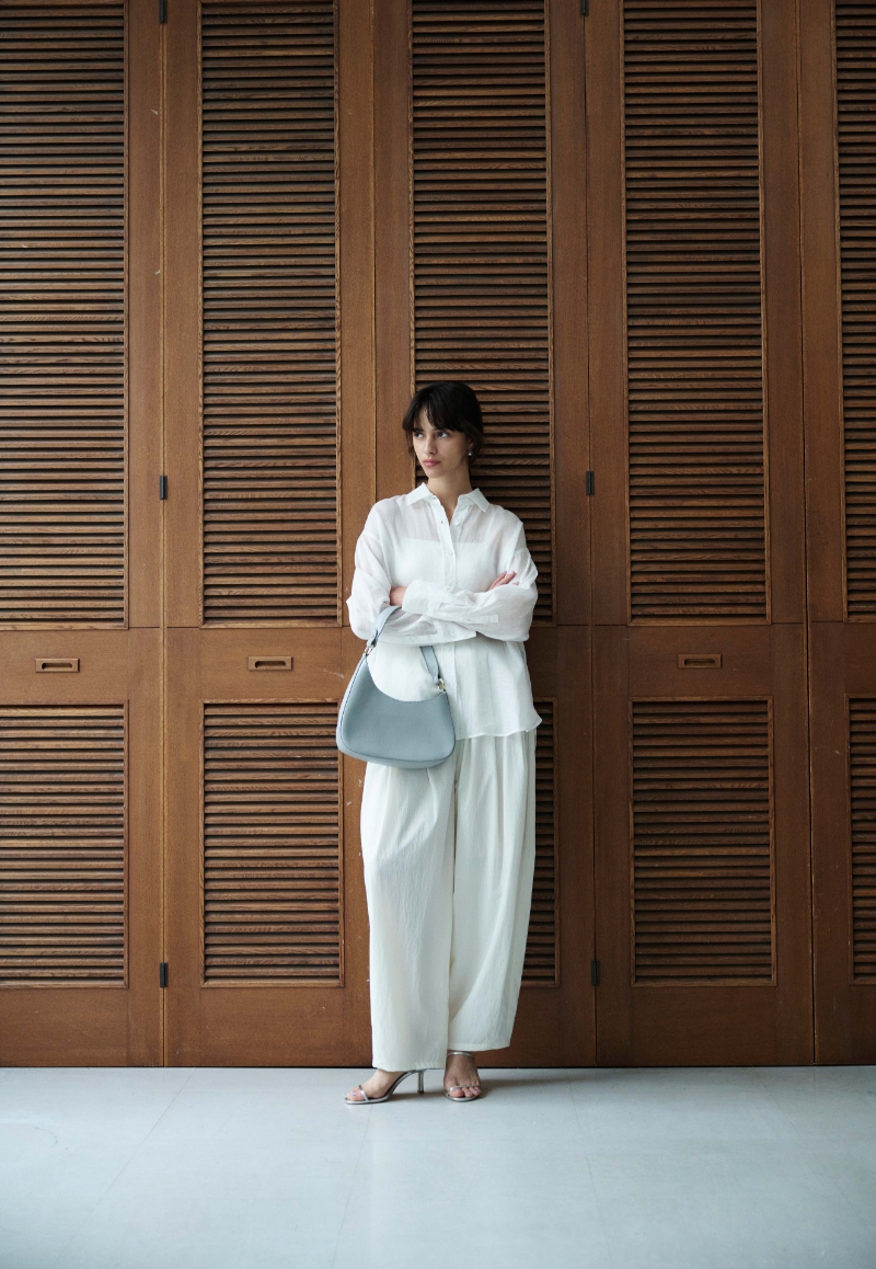 ホワイトのシアーシャツ・ホワイトのパンツ・パステルブルーのバッグを着用した女性--2