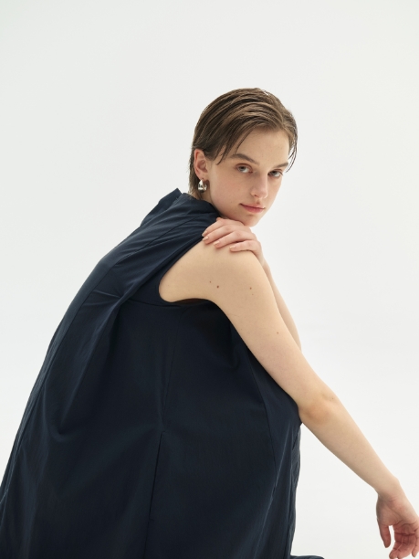 ネイビー色のナイロンタスランワンピース【AIRY MOTION】を着用して座ってる女性