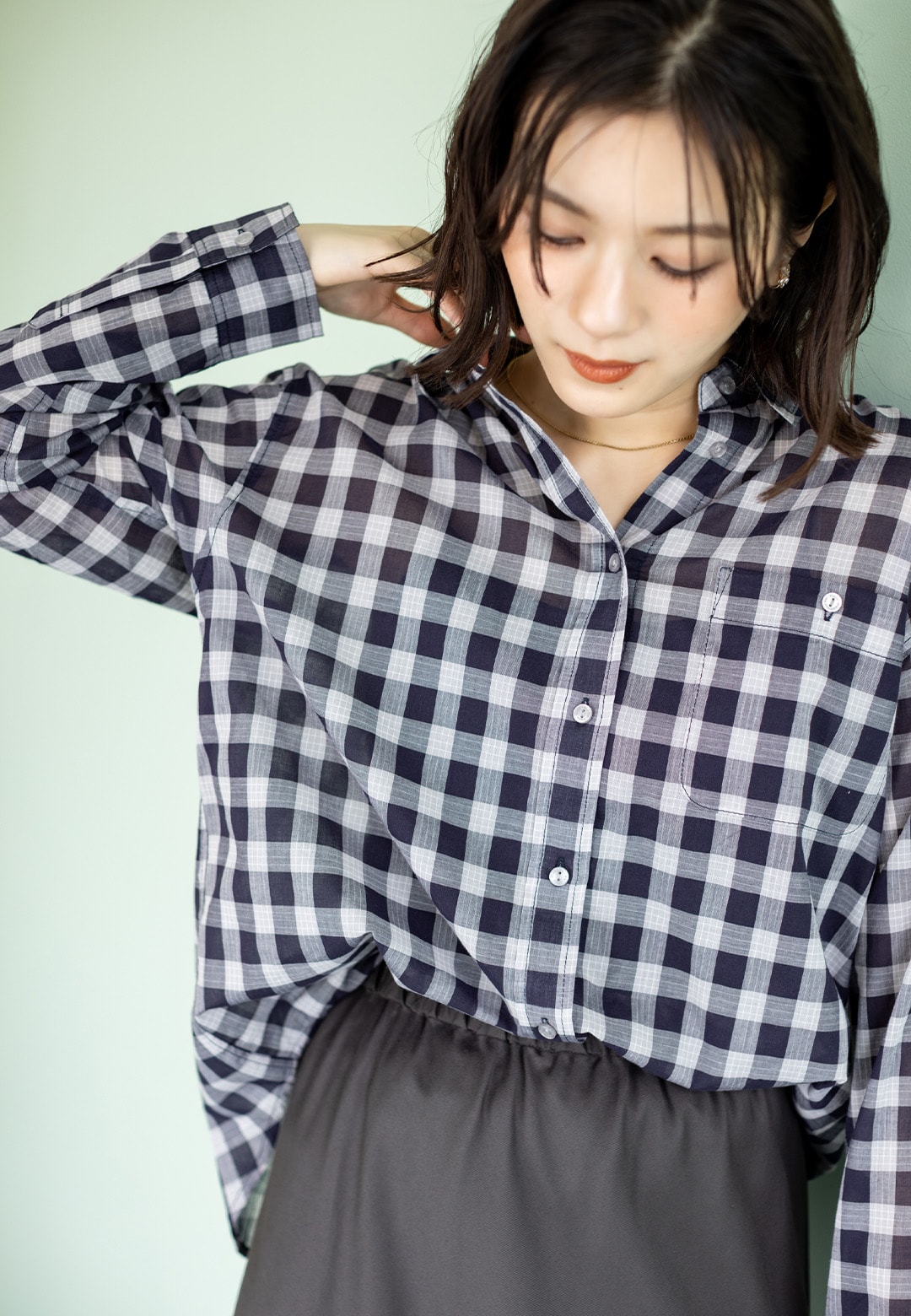 レギュラーカラーシアーチェックシャツとマーメイドラインスカートとスタッズ巾着2WAYバッグを着用した女性２