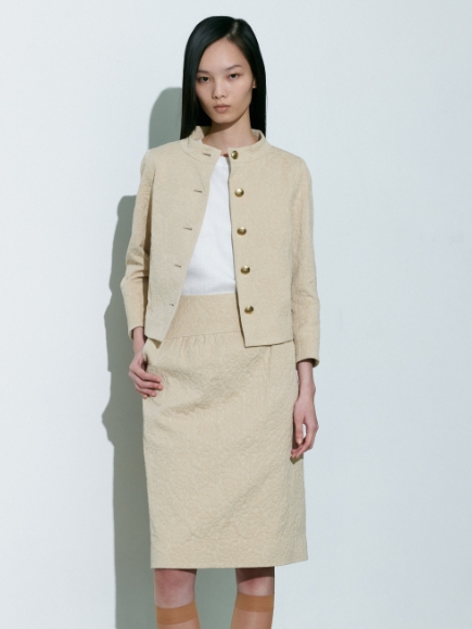 ベージュ色のJacket、Skirtと白色のPulloverを着用している女性の画像